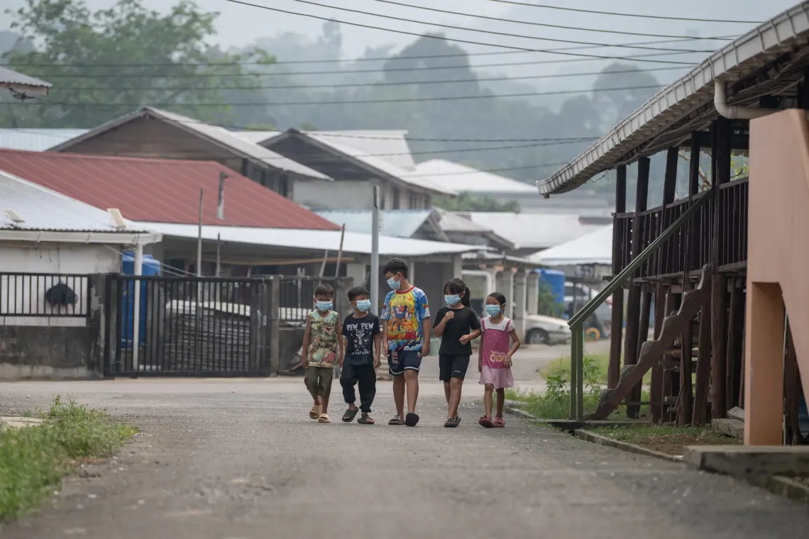 Five children wearing face masks walk together through their neighbourhood under hazy skies.