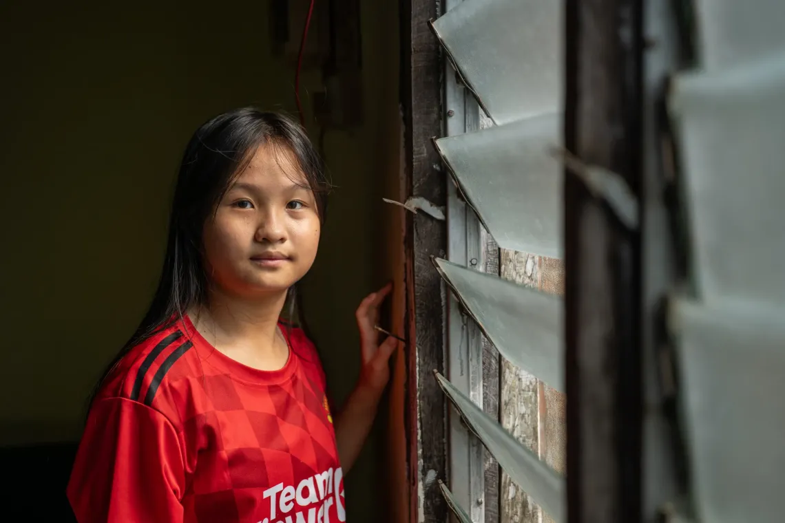 Eva, 12, stands by a window at her home in Kampung Mongkos, Serian, Sarawak.