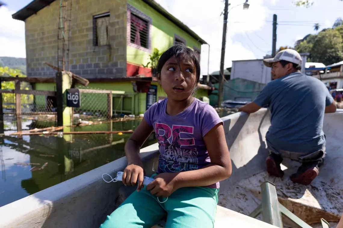 A child sitting in a boat with a concerned look on her face.