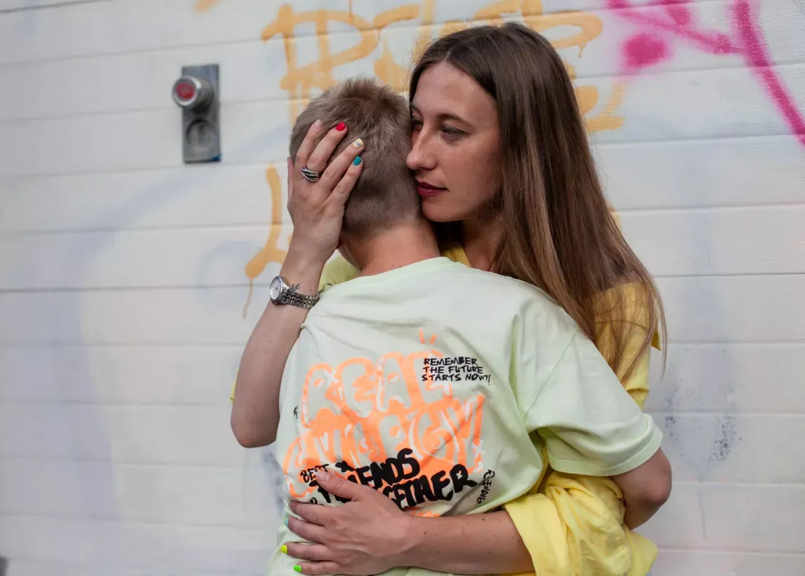 A woman comforting a child by hugging them
