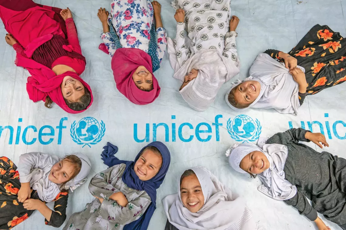 girls pose at the entrance to a UNICEF-supported community-based education centre in Hijrat Mina in Bagrami District, Kabul Province, Afghanistan.