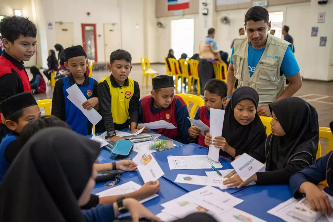 Under Sufyan's guidance, students engage in various activities designed for all ages. They start with coloring and jigsaw puzzles featuring images of common disasters like landslides and floods, learning about the risks in a fun and interactive way.