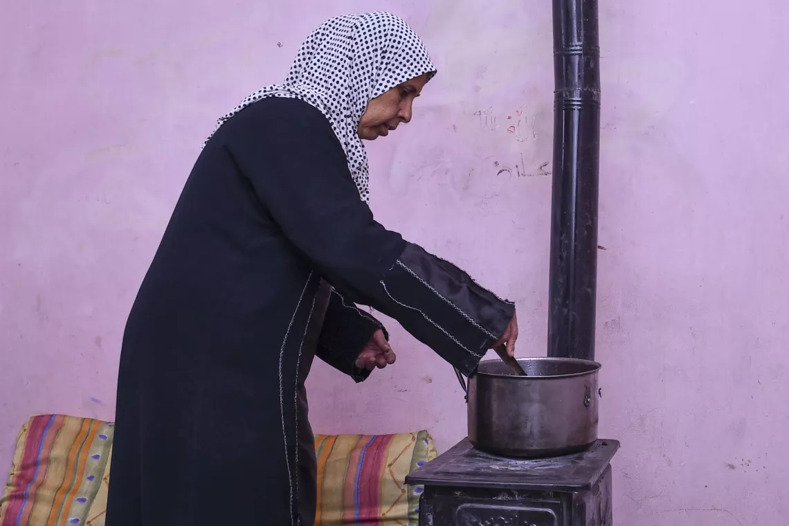 Farha, 45, cooks a meal on a wood stove in her apartment in Shabaa village, Rural Damascus.