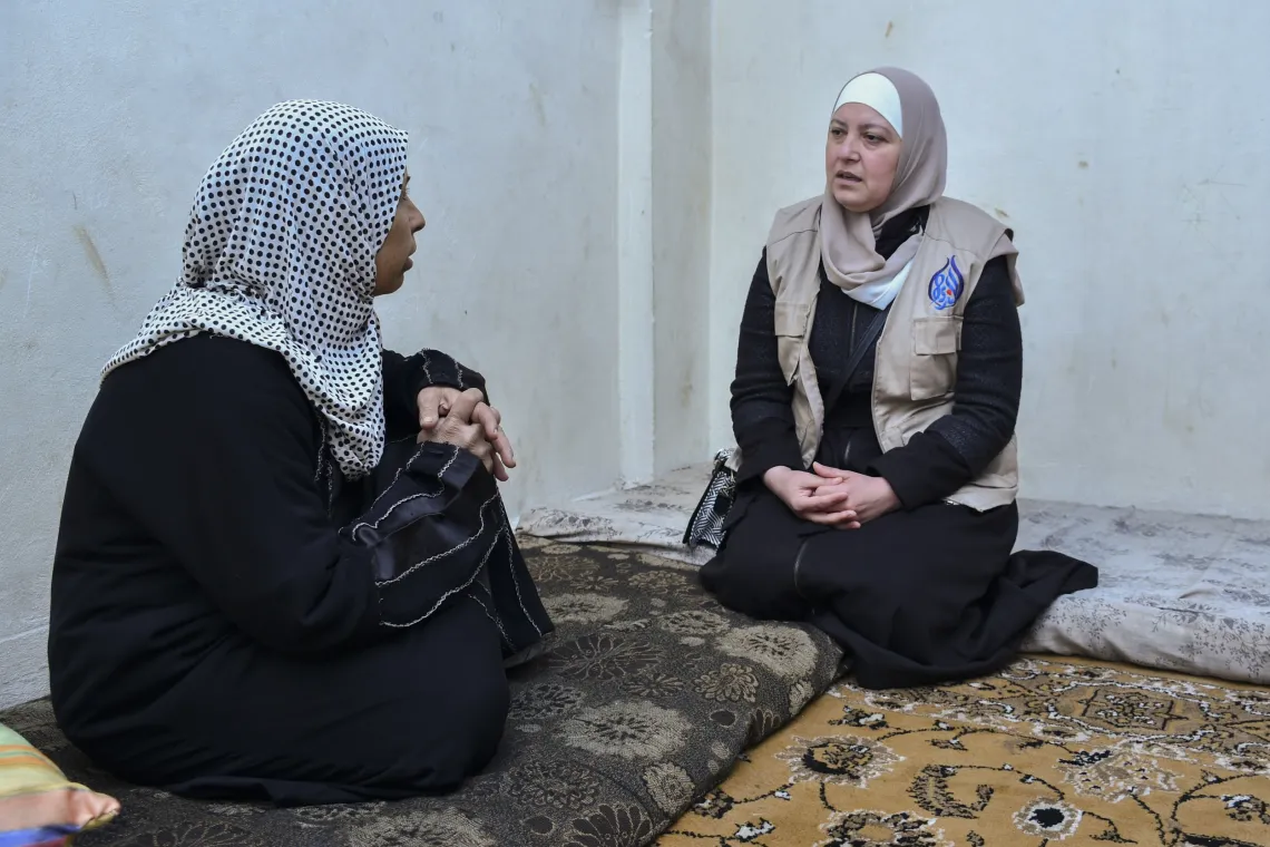 Farha, 45, speaks with a humanitarian worker from a UNICEF-supported team in her apartment in Shabaa village, Rural Damascus.