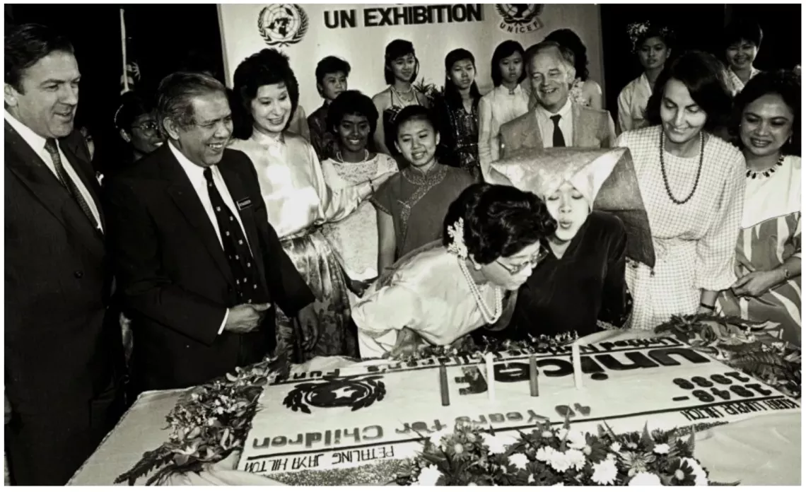 Tun Dr. Siti Hasmah blows candles out on a UNICEF cake at an official function in Malaysia.