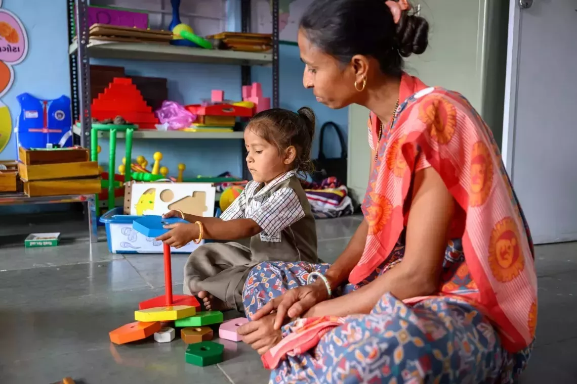 A mother watching over her child playing with toys