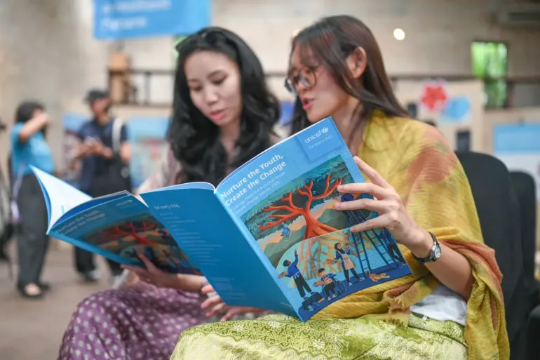 Two young women read the NYCC report