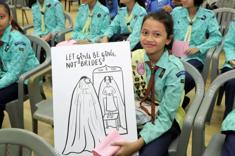 girl guide holding anti-child-marriage poster