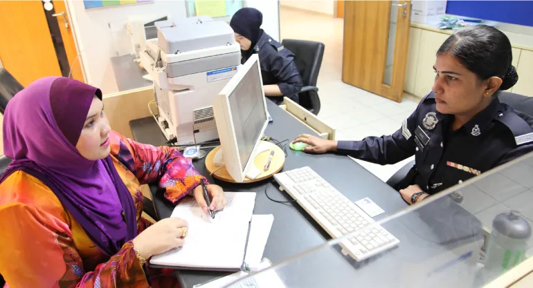 A social worker from the Department of Social Welfare lodges a report of child abuse with an officer at the police station