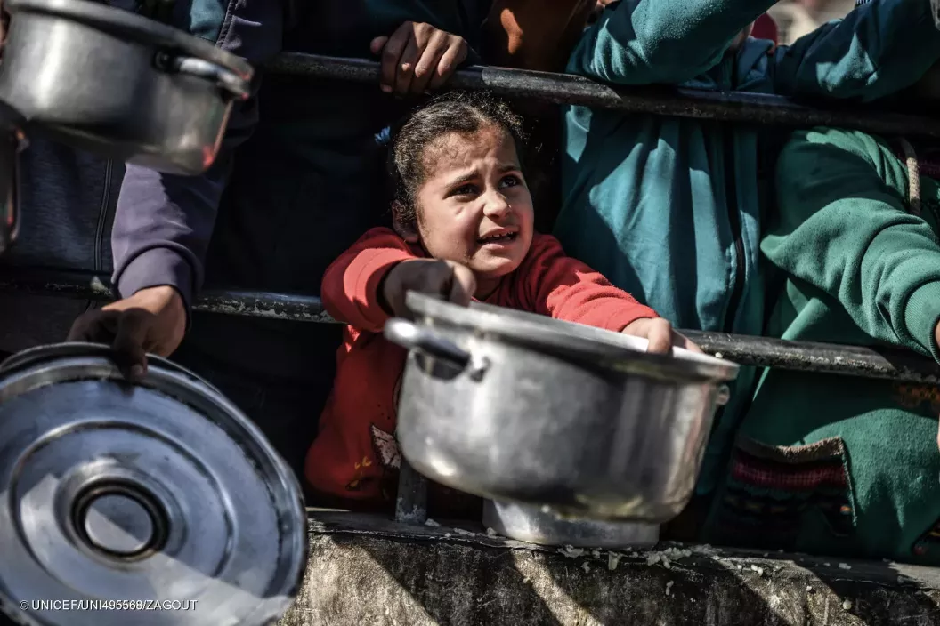 Shaima, 8-years-old, waits her turn in the crowd to get a meal from a charitable hospice that distributes free food in the city of Rafah, southern Gaza Strip.