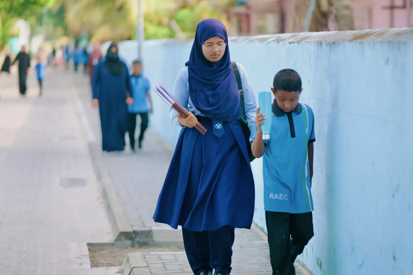 An older sister and her younger brother walking home from school together