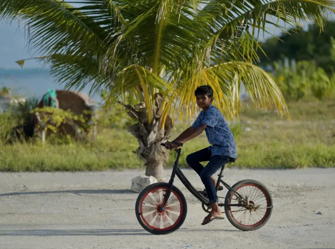 A young boy riding a bicycle on an island road 