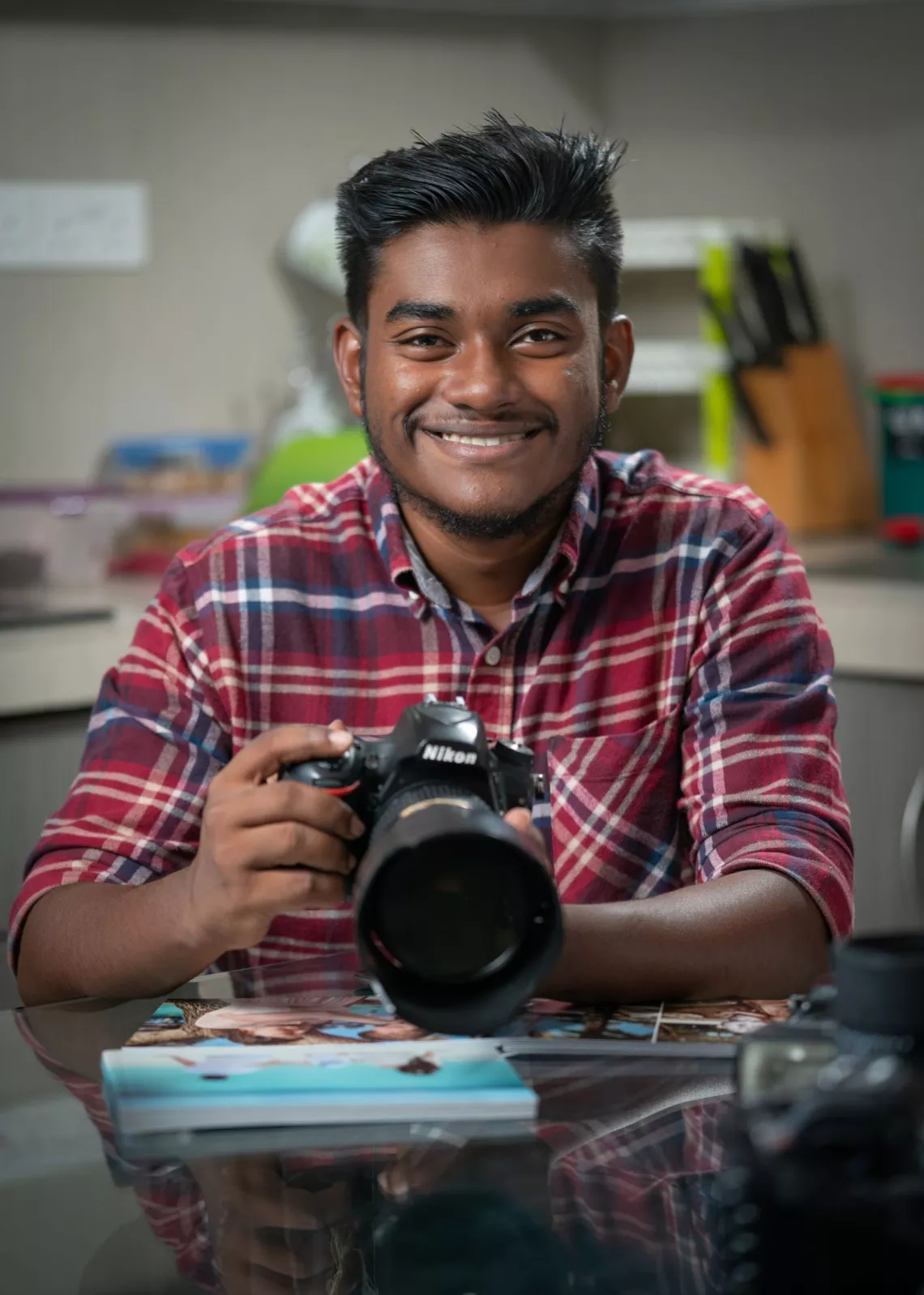Youth sitting at a table with a camera in hand