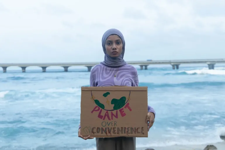 A girl holding a protest sign and looking at the camera