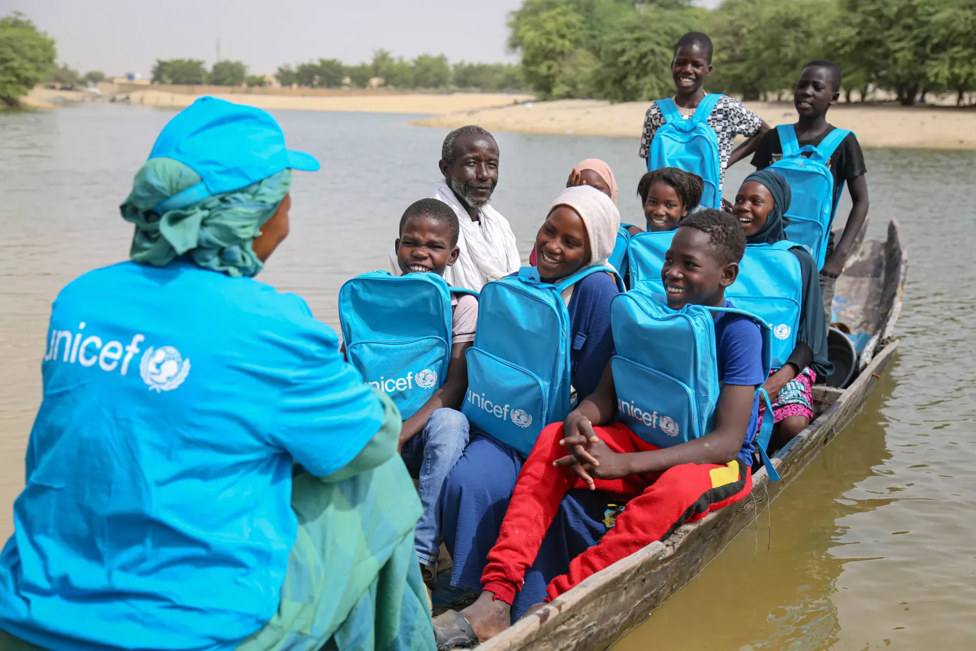 Fatoumata Hamadoun, Charg&eacute;e de l&rsquo;&eacute;ducation pour l&lsquo;UNICEF &agrave; Tombouctou, accompagne ici les enfants en pirogue pour traverser le canal dans le quartier Djingareyber de Tombouctou, juste apr&egrave;s la remise de leurs kits scolaires.   Fatoumata Hamadoun, Education Officer for UNICEF in Tombouctou, here with school children in a canoe as they cross a canal in the Djingareyber neighborhood of Tombouctou, shortly after the distribution of their school kits. 