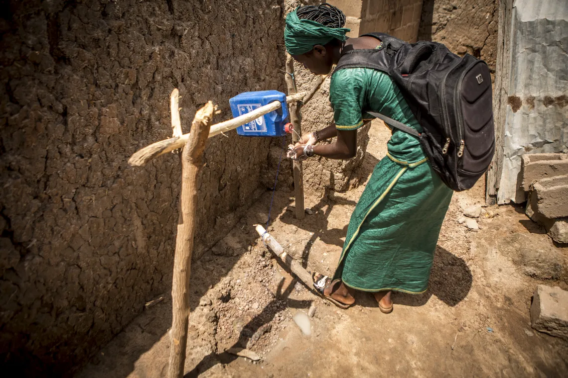 Mawa Berthe 12 ans, &eacute;l&egrave;ve en classe de 6&egrave;me &agrave; l&rsquo;&eacute;cole fondamentale de Sougoumba, elle se lave les mains &agrave; l&rsquo;aide d&rsquo;un dispositif de lavage de mains localement fabriqu&eacute; install&eacute; dans leur famille. Village de Soungoumba, commune rurale de Koningu&eacute;, r&eacute;gion de Sikasso, Mali, Octobre 2019