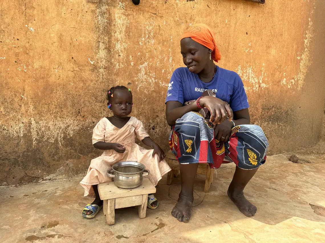 Kadia, une maman refugi&eacute;e Burkinabaise, &acirc;g&eacute;e de 25 ans, ici avec sa fille Mariam, &acirc;g&eacute;e de deux ans et demi dans la famille qui les accueille. Mariam compl&egrave;tement gu&eacute;rie prend son d&eacute;jeuner avec app&eacute;tit. Kadia, a Burkinabe refugee mother, aged 25, here with her daughter Mariam, aged two and a half, in the family that welcomes them. Mariam, completely healed, eats her lunch with gusto.