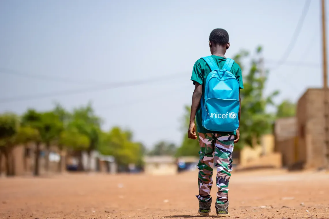 Mahamadou on his way to school in Markala and proud of his school supplies.