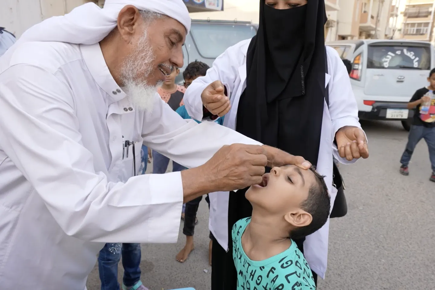 Dr. Nabil vaccinating administering polio drops to one of his grandsons in front of the community to convince people about the safety of the polio vaccine. Yemen, 2022