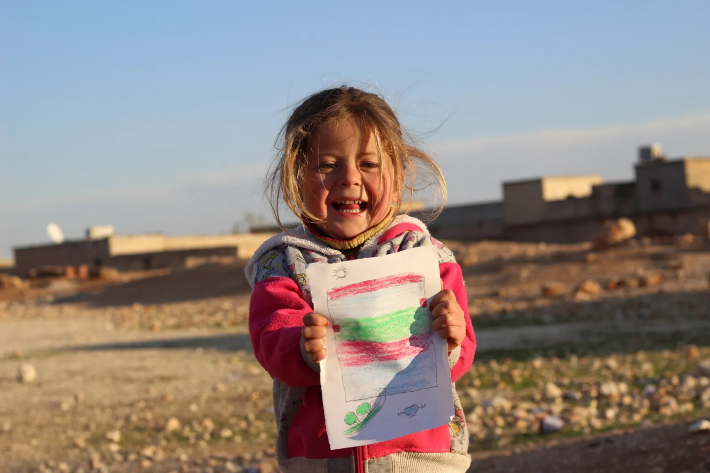 a girl holds up a drawing
