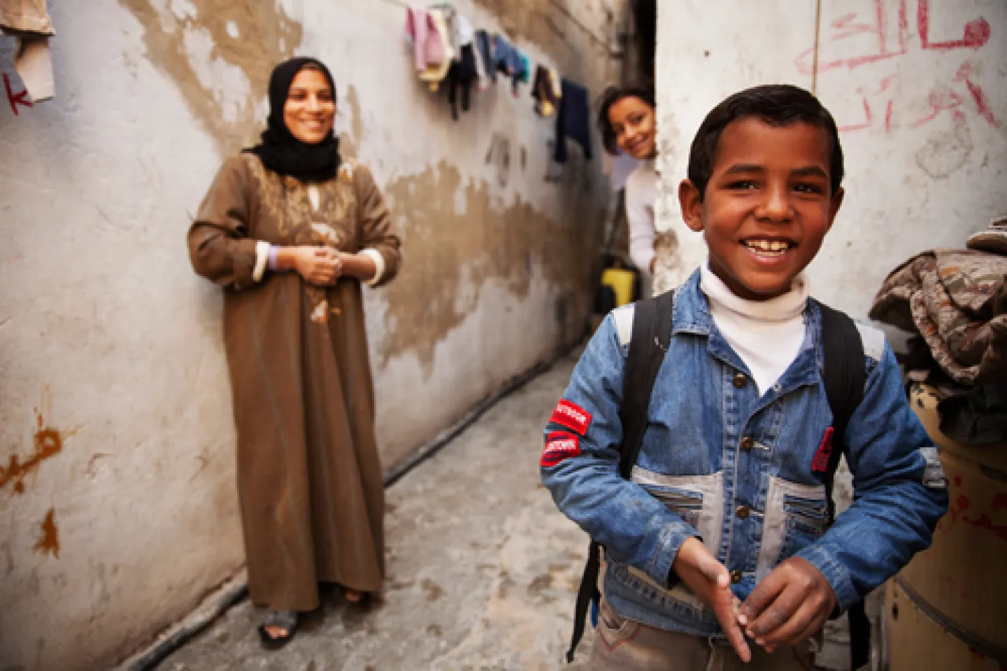 a boy carrying a backpack with his mother nad sister in the background
