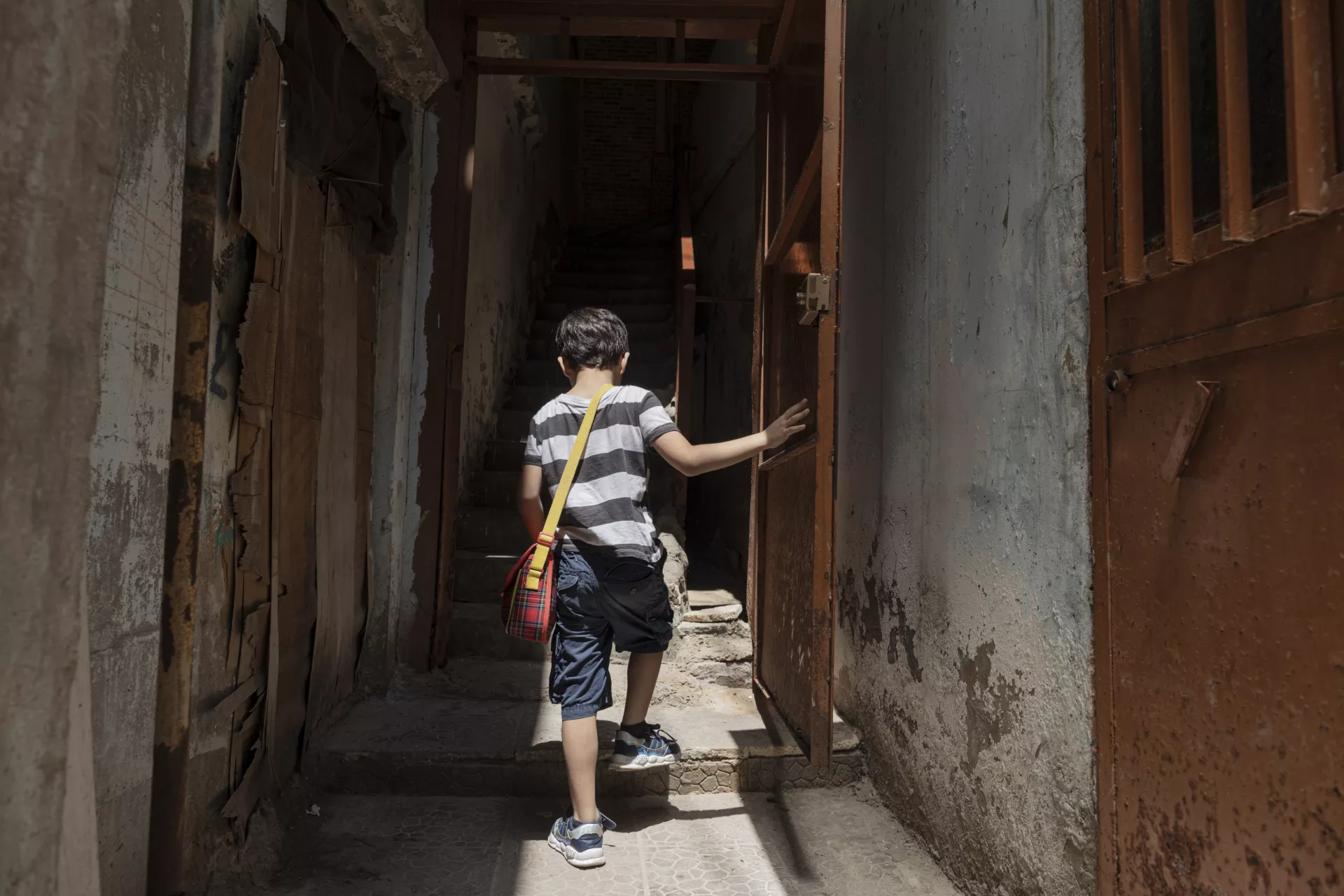 Omar, 6, a third-generation Palestinian refugee who was born in Lebanon, opens the door to his home in Burj al Barajneh informal settlement