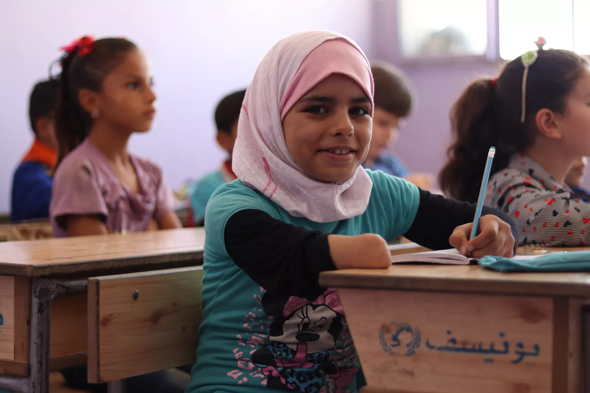 A young girl with one hand writes in school