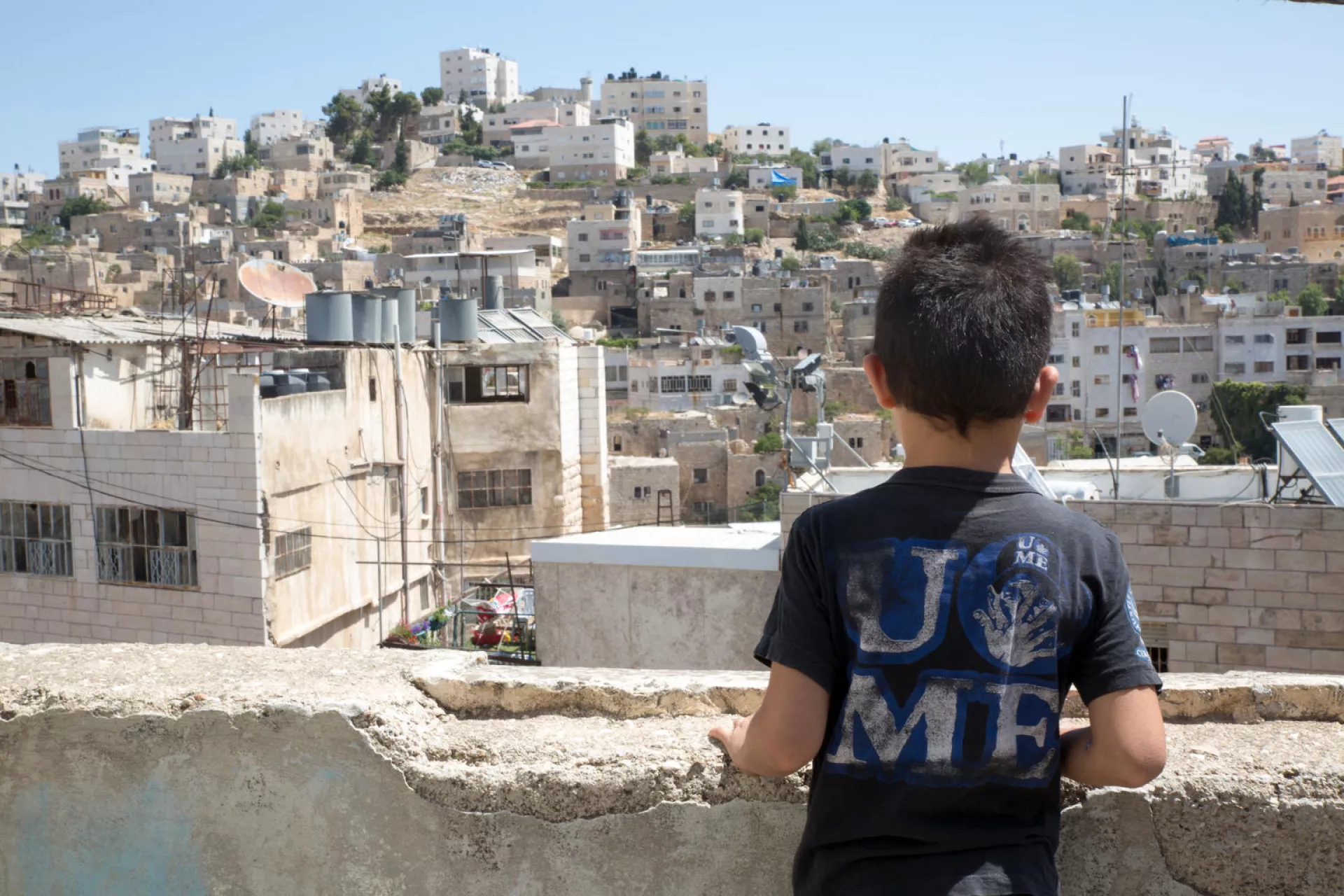 a boy looking over a town from a rooftop 