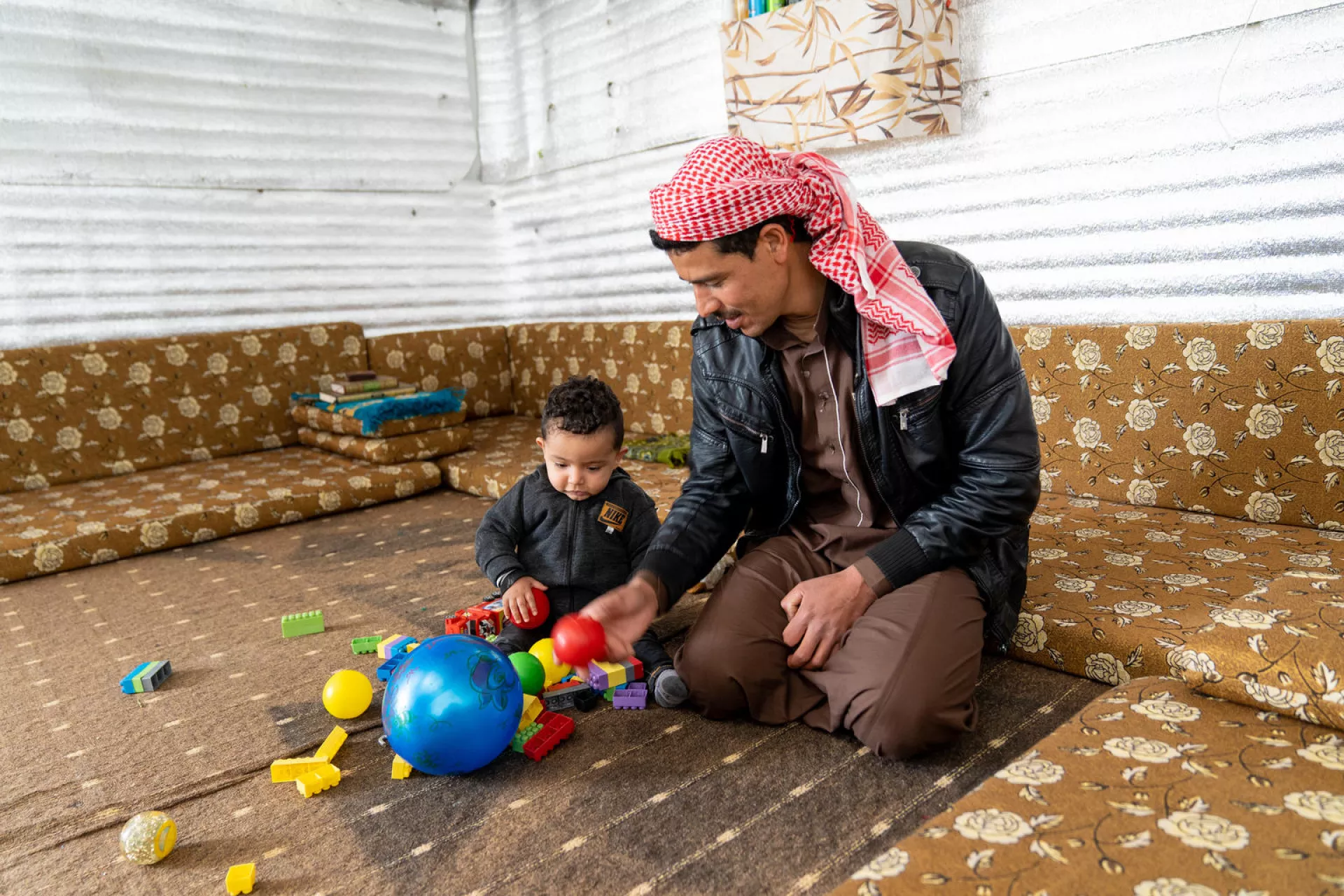a father plays with his baby boy with balls