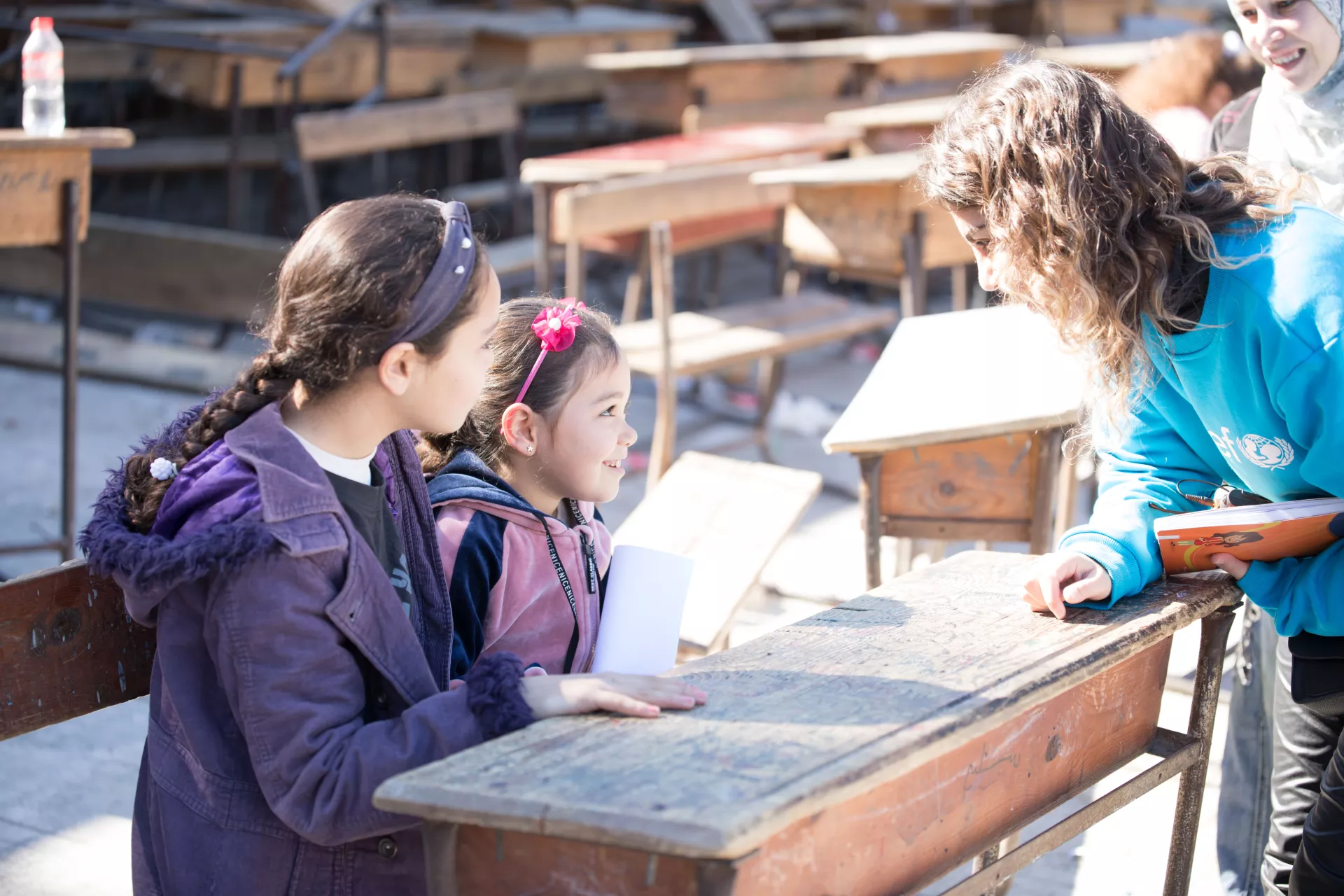  Maysaa, 13, and her six-year-old sister, Renad, talk with a UNICEF staff member in their shelter in Stamo village, Lattakia governorate, Syria. Renad holds a drawing she made earlier that day.
