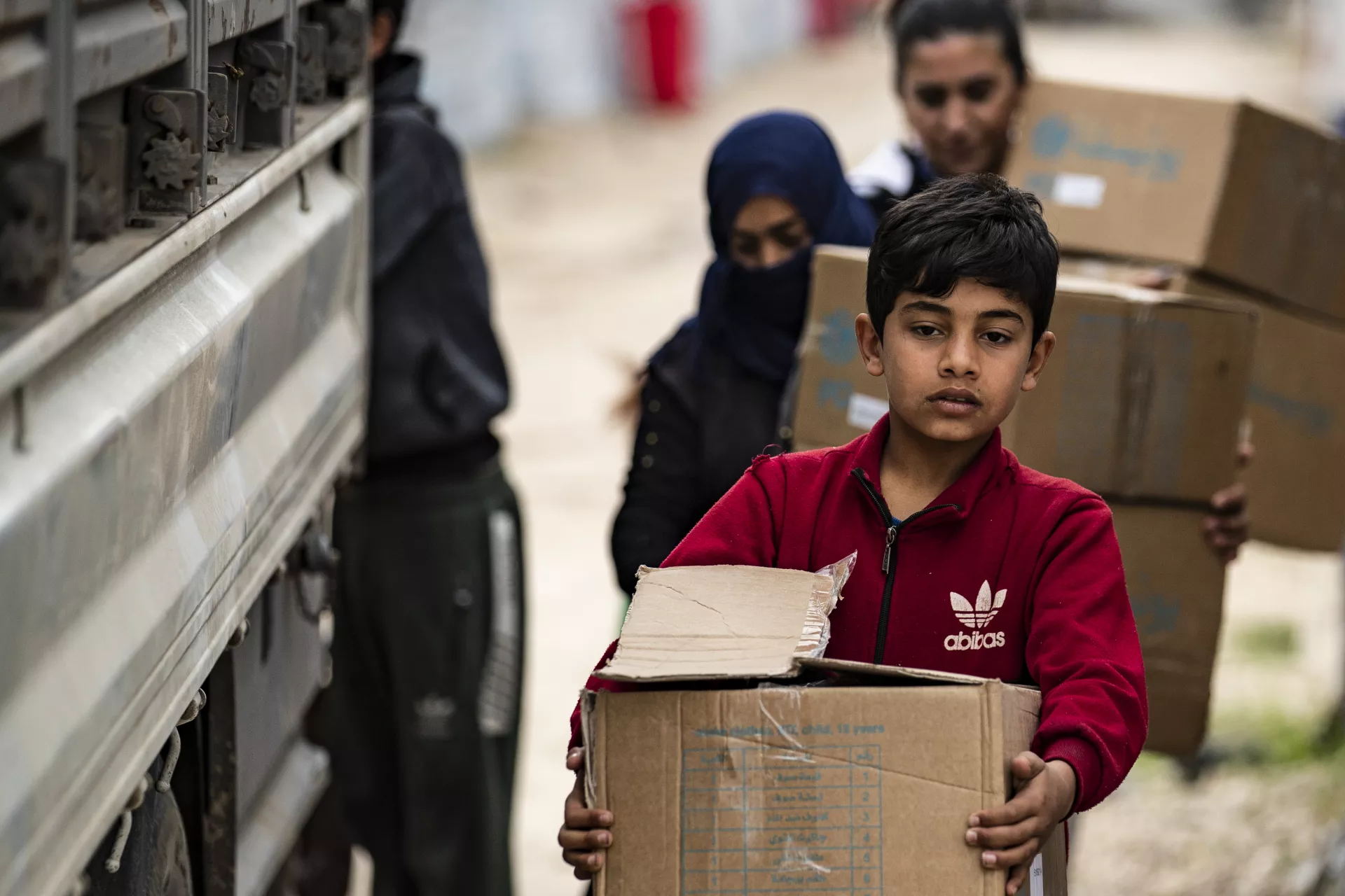 Ahmad, 12, helps his mother carry the family&rsquo;s newly received winter clothing kits, distributed by UNICEF in Roj camp, northeastern Syria.