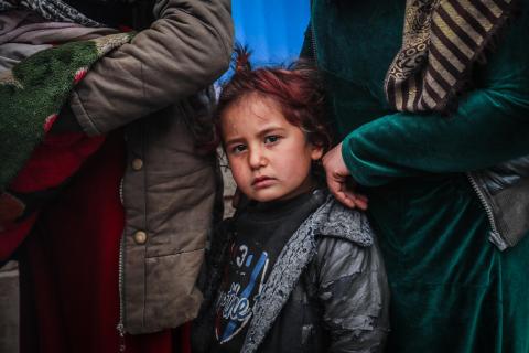 A young girl stands in line and looks at the camera.