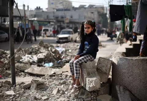 Maha, an 11-year-old, is sitting on the rubble of a house in Rafah, southern the Gaza Strip.