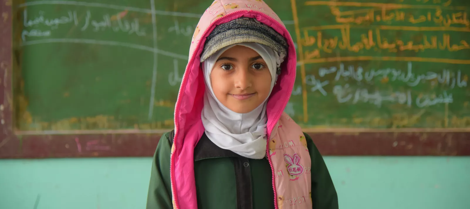 A portrait of a girl standing in front of a blackboard in the classroom