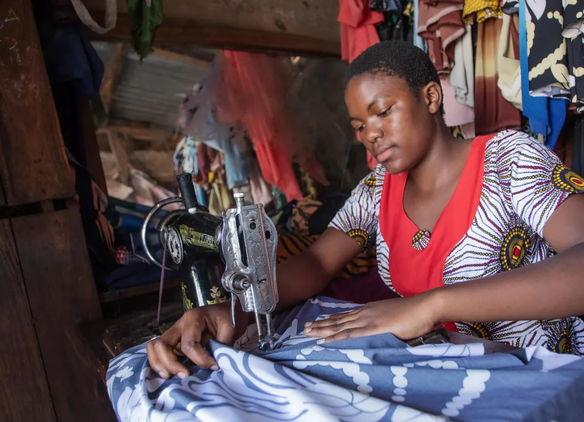 Antini works on a blue and white dress at her sewing machine.
