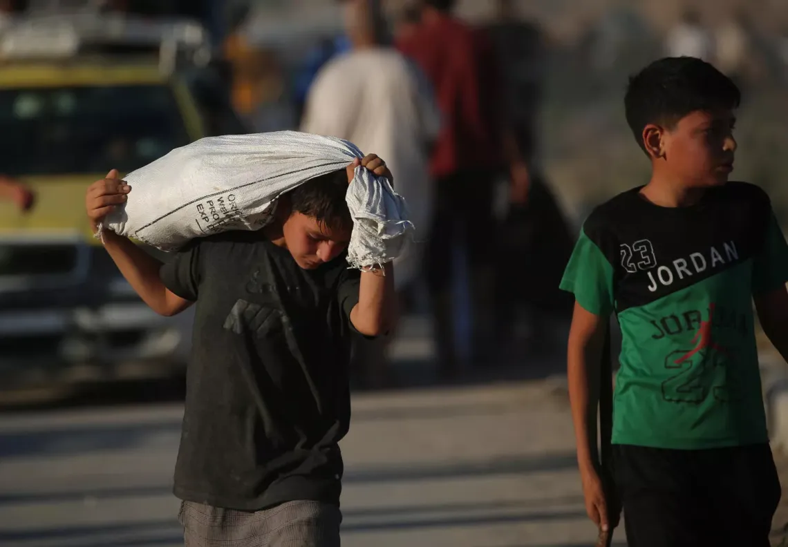 Gaza. A boy carries a sack of supplies over his shoulders near a distribution point near Netzarim.