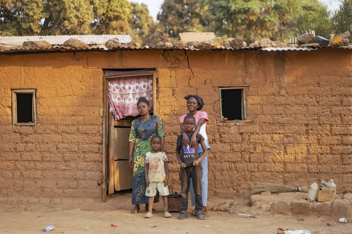 Astride stands smiling with her hands over her brother's shoulders, next to her mother and youngest sibling.