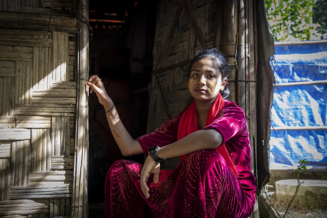 Kulsum sits in the doorway, resting one hand on the frame.