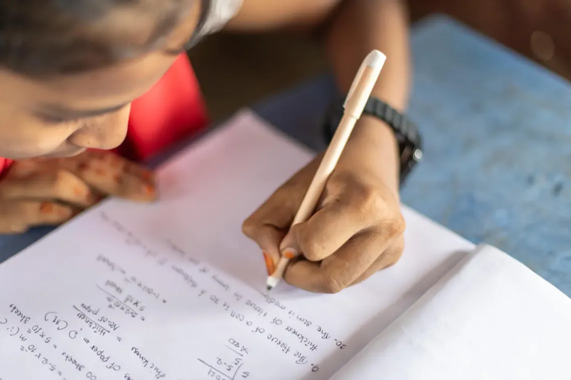 Kulsum writes in a notebook during class at the learning centre.