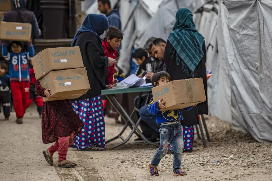 Children and families carry their newly received winter clothing kits, distributed by UNICEF in Roj camp, northeastern Syria.