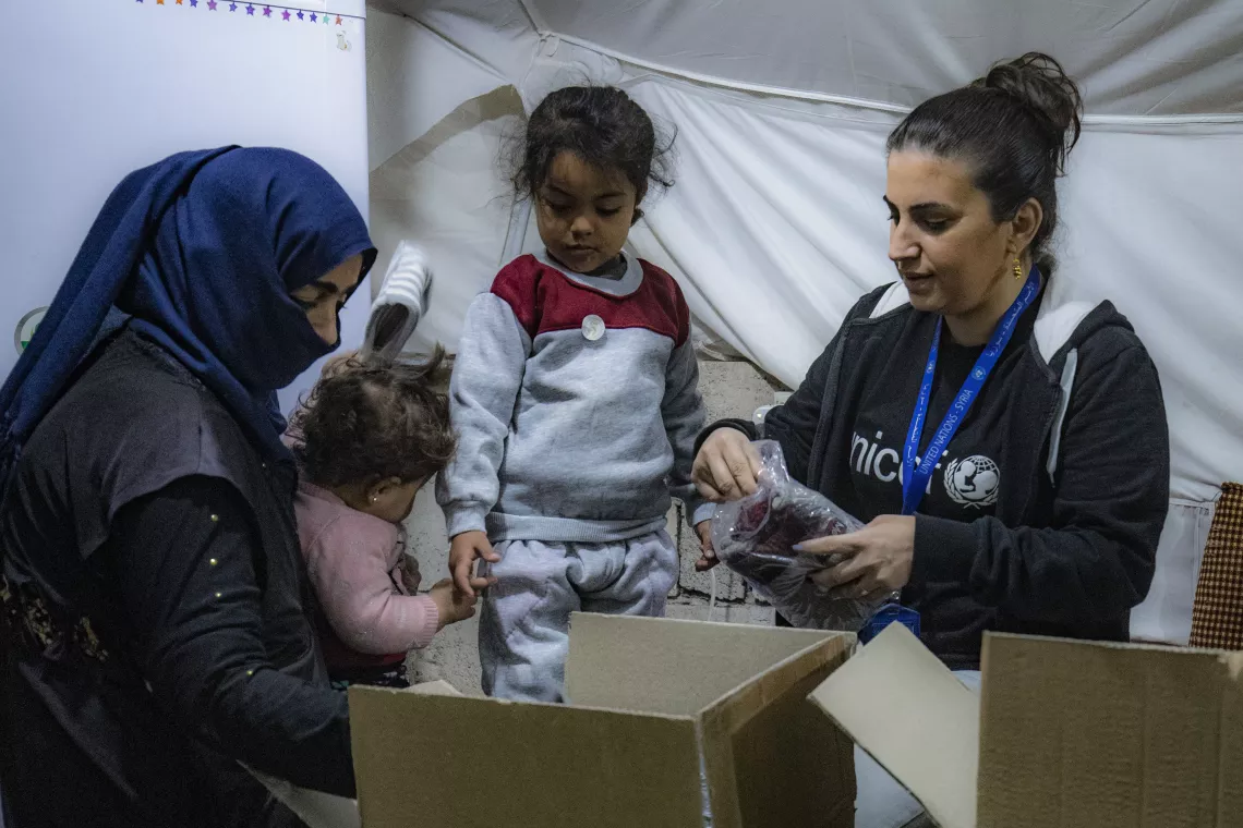 UNICEF staff members talks to families after receiving their new winter clothing kits distributed by UNICEF in Roj camp, northeastern Syria.