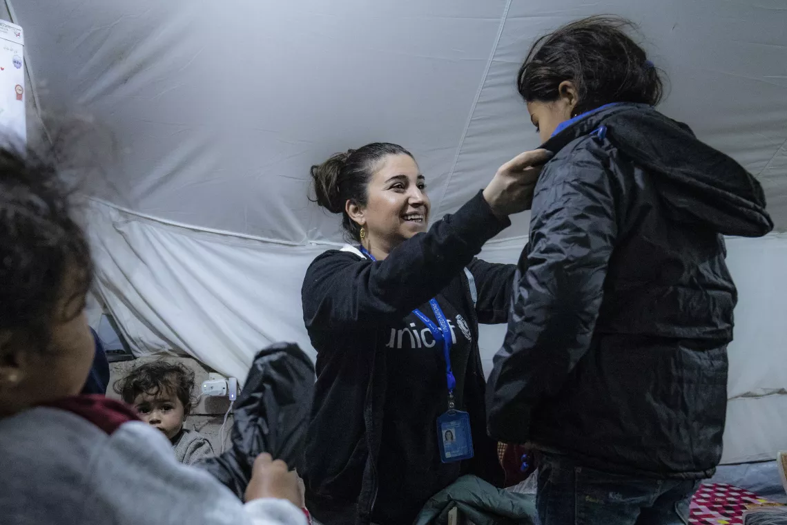 UNICEF staff members talks to families after receiving their new winter clothing kits distributed by UNICEF in Roj camp, northeastern Syria.