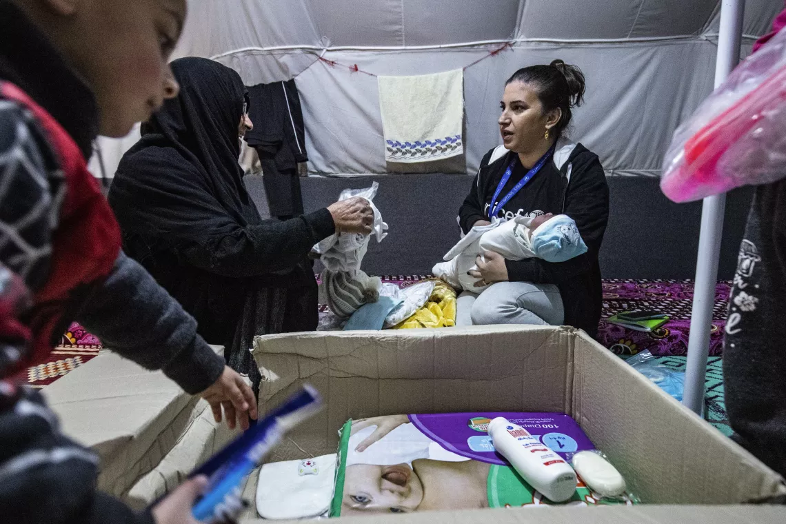 UNICEF staff members talks to families after receiving their new winter clothing kits distributed by UNICEF in Roj camp, northeastern Syria.