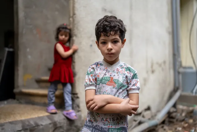 Khaled 7 years old standing in front of his house with his sister standing behind him.