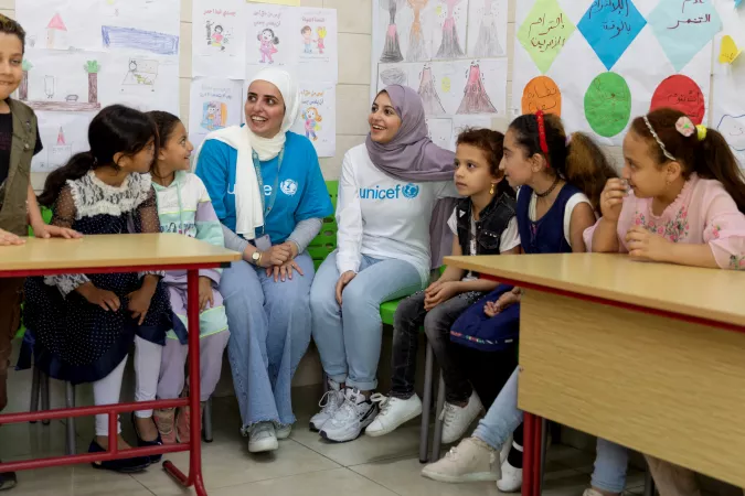 On 31 August 2022, UNICEF Goodwill Ambassador Muzoon Almellehan (white UNICEF T-shirt) and Alaa Khaled Hasan (cyan T-shirt), UNICEF Makani Officer, sit in on a Child Protection session while visiting a UNICEF-supported Makani centre in East Amman, Jordan.