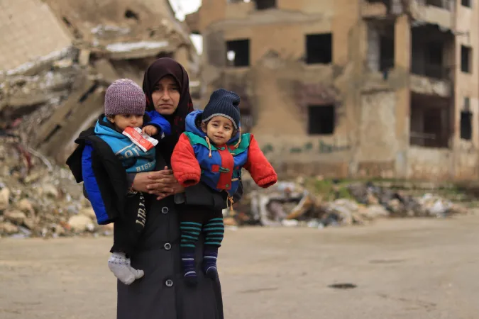 Syria. A woman holds her children.