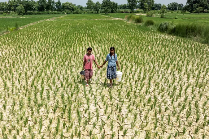 Two girls walk in a dry field. 