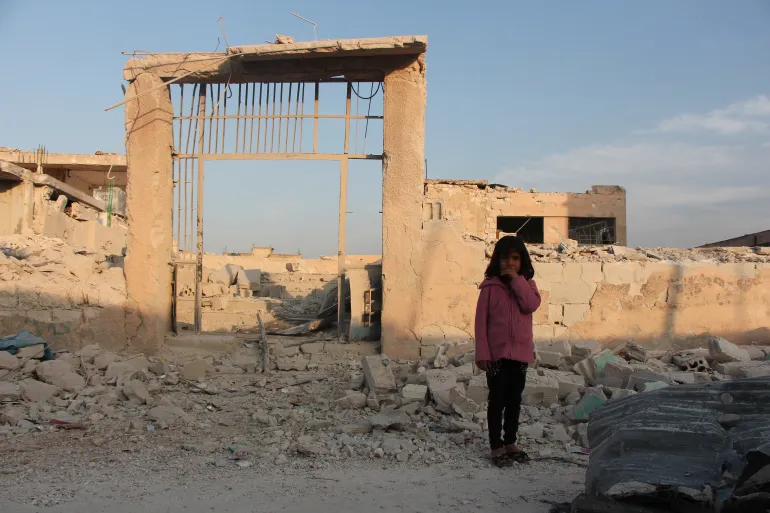 Young girl standing infront of rubble 