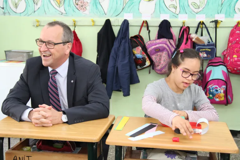 UNICEF Regional Director sitting at a desk with a girl in a school