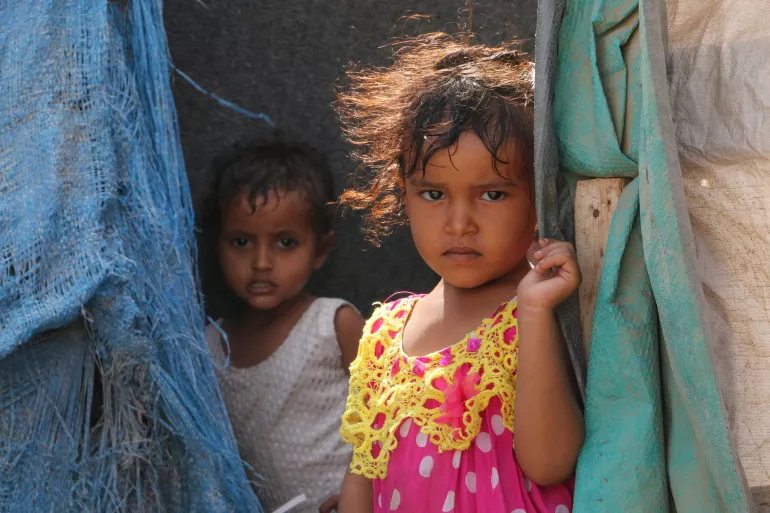 Two children looking from behind their tent drapes